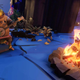 A strange astronaut sits by a fire and plays guitar.